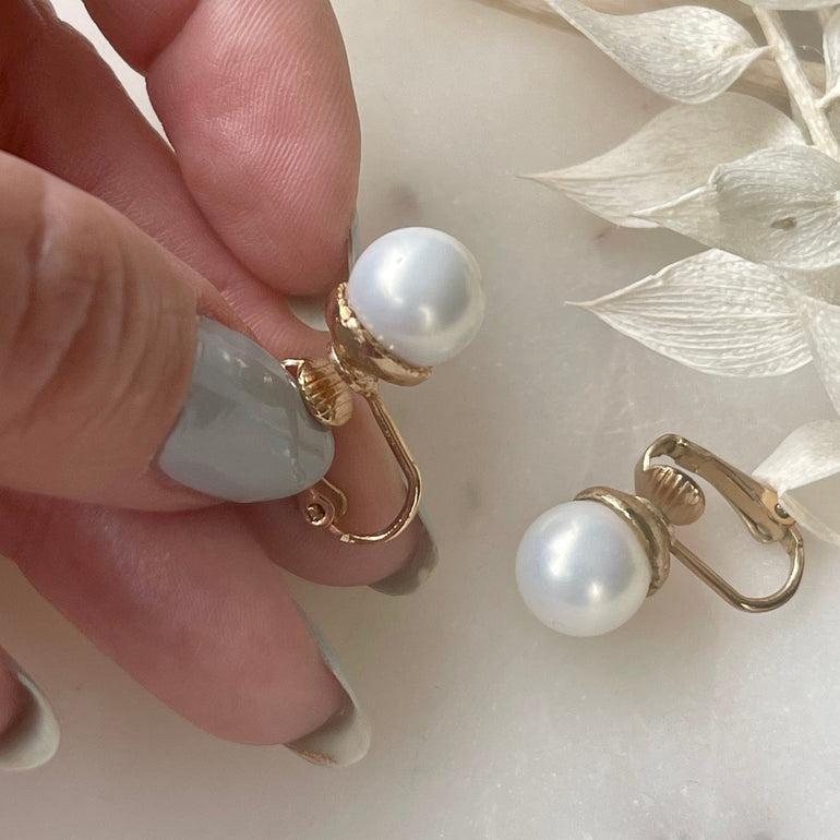 Die vergoldeten "ELLA" Perlenohrringe mit Kunstperlen und Clip-Verschluss sind mit ca. 1,0 cm Durchmesser zart und vielseitig. Ein klassisches Design, das jedem Anlass eine subtile Eleganz verleiht – perfekt für zeitlose Schönheit