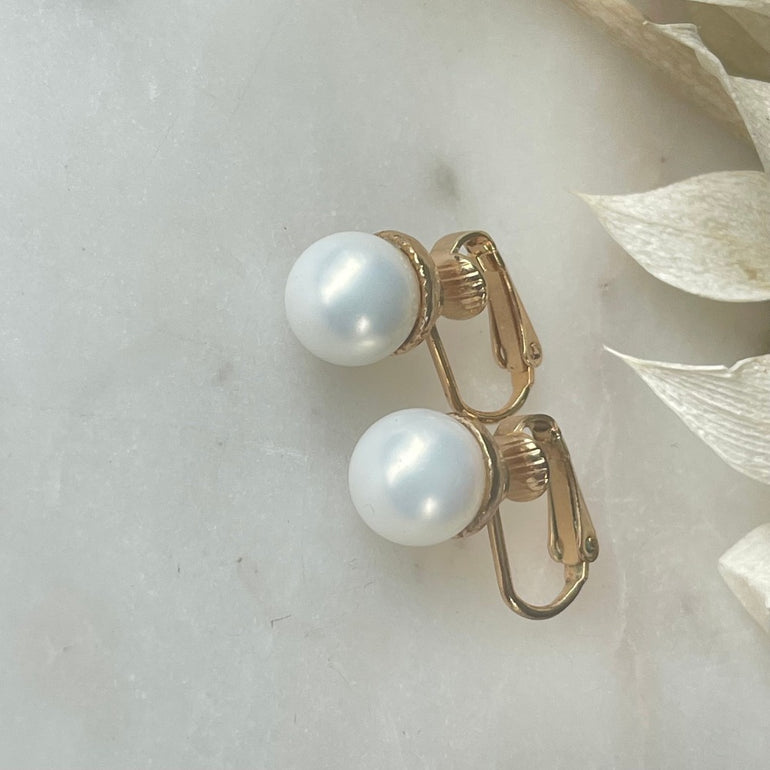 Die vergoldeten "ELLA" Perlenohrringe mit Kunstperlen und Clip-Verschluss sind mit ca. 1,0 cm Durchmesser zart und vielseitig. Ein klassisches Design, das jedem Anlass eine subtile Eleganz verleiht – perfekt für zeitlose Schönheit