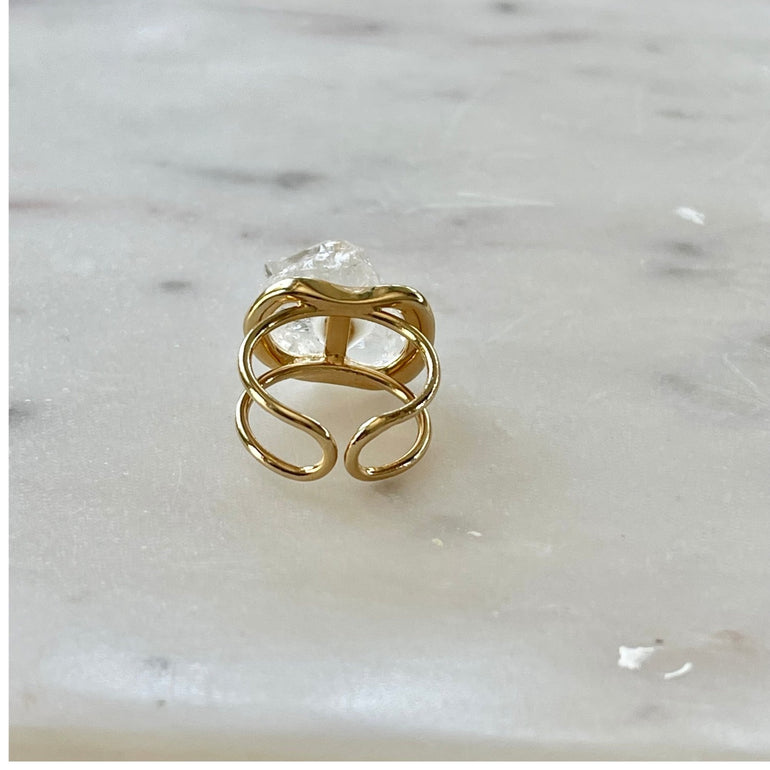 Der Ring "ÉRIKA", vergoldet mit 18 K Bergkristall, ist ein unverwechselbares Stück.  Ein offener Cocktailring in transparentem Design. Verstellbar.  Aus hochwertigem, 18 K vergoldetem Messing mit natürlichem Bergkristall. Perfekt für Frauen, die besondere und einzigartige Stücke zu schätzen wissen.
