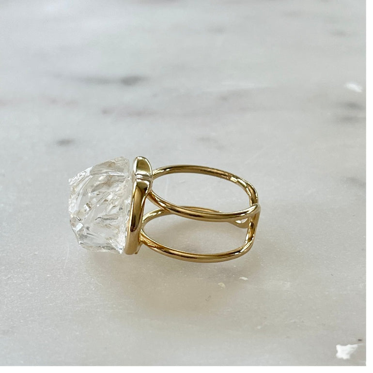 Der Ring "ÉRIKA", vergoldet mit 18 K Bergkristall, ist ein unverwechselbares Stück.  Ein offener Cocktailring in transparentem Design. Verstellbar.  Aus hochwertigem, 18 K vergoldetem Messing mit natürlichem Bergkristall. Perfekt für Frauen, die besondere und einzigartige Stücke zu schätzen wissen.