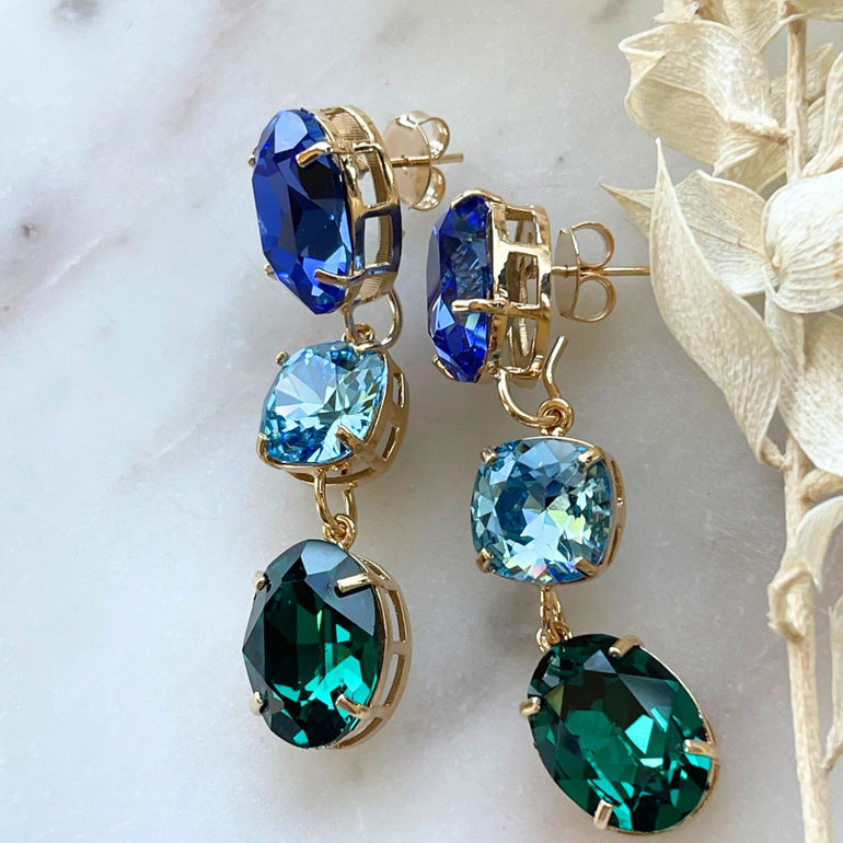 Entdecken Sie unsere "GLOW"-Ohrringe mit blau-grünen Kristallen. Die grüne Basis kann allein getragen werden und verleiht einen dezenten, aber wunderschönen Look. Die weltberühmten Kristalle sorgen für Glanz und zeitlose Eleganz.