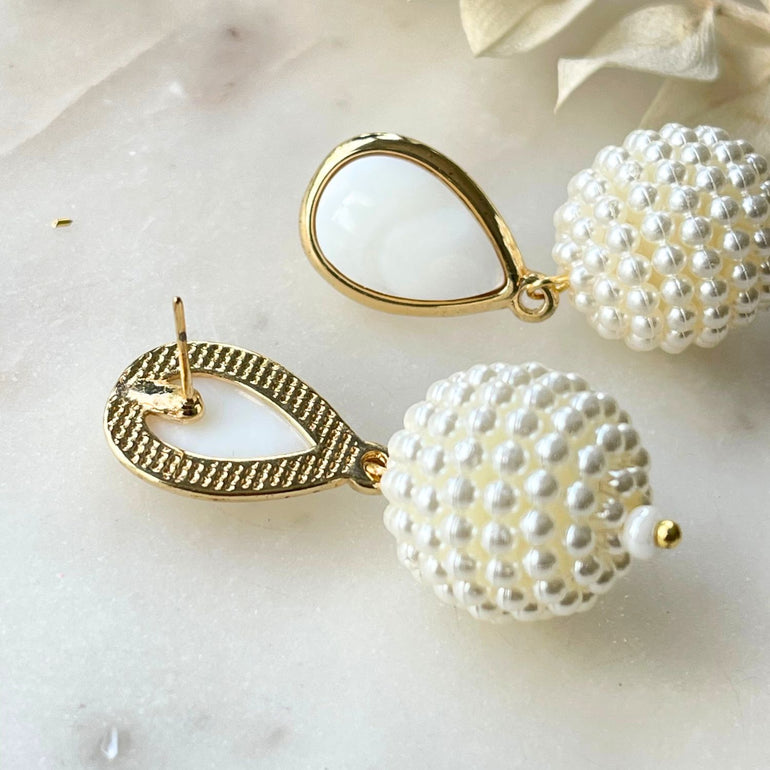 Die 'Perlen Ohrringe Little DAISY' sind exquisite Ohrringe mit einem Stecker-Verschluss. Die Permutt-Basis hat eine Breite von 1,5 cm, während die Gesamtlänge, einschließlich Basis und Anhänger, etwa 4 cm beträgt. Diese eleganten Ohrringe bestehen aus 18 K vergoldetem Messing in Kombination mit Permutt.