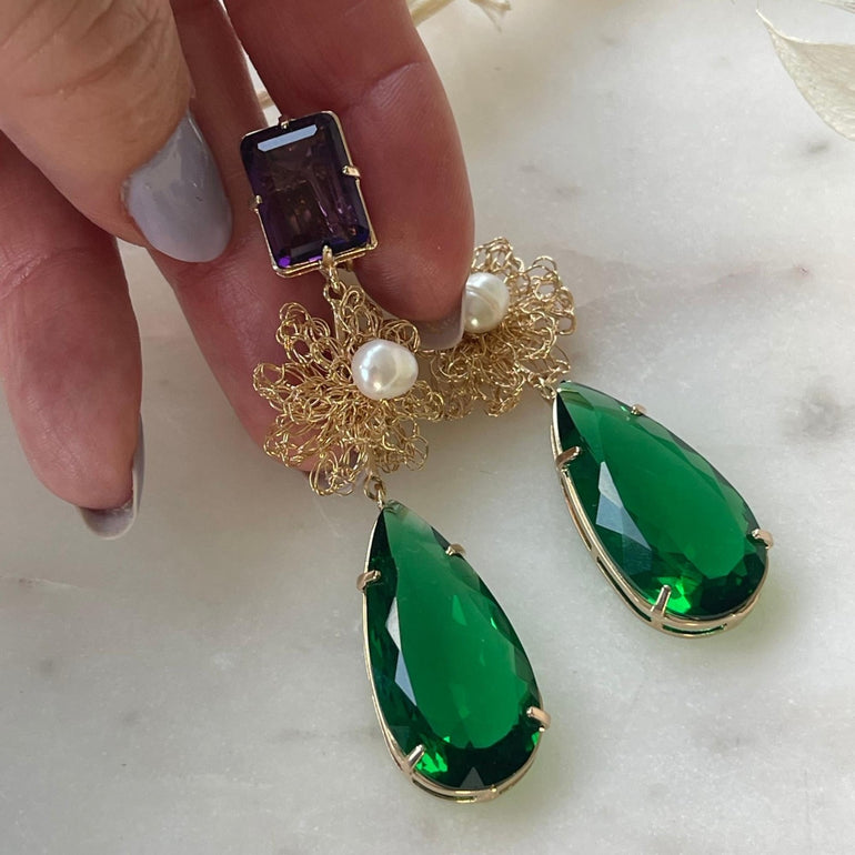 Ohrclip LE CLOS NORMAND: Eleganter und vielseitiger Schmuck mit grünen und lila Kristallen. Clip-Verschluss, Länge: 6,7 cm, Breite: 1,1 cm. 18 K vergoldetes Messing mit funkelnden Kristallen in den Farben Lila und Smaragd. Enthält ein komplettes Ohrring-Paar sowie zusätzliche lila Kristalle für vielseitiges Styling