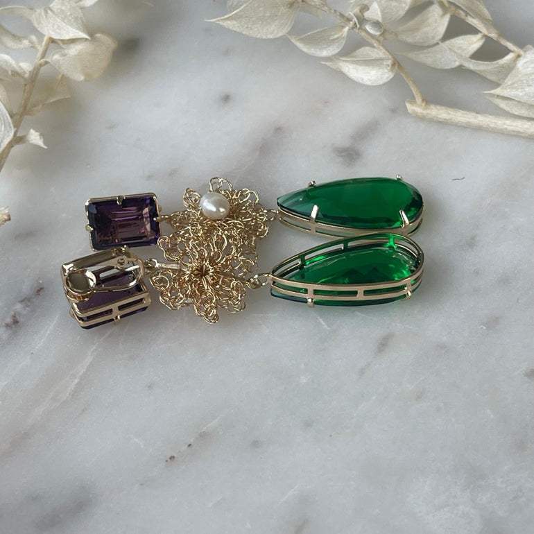 Ohrclip LE CLOS NORMAND: Eleganter und vielseitiger Schmuck mit grünen und lila Kristallen. Clip-Verschluss, Länge: 6,7 cm, Breite: 1,1 cm. 18 K vergoldetes Messing mit funkelnden Kristallen in den Farben Lila und Smaragd. Enthält ein komplettes Ohrring-Paar sowie zusätzliche lila Kristalle für vielseitiges Styling