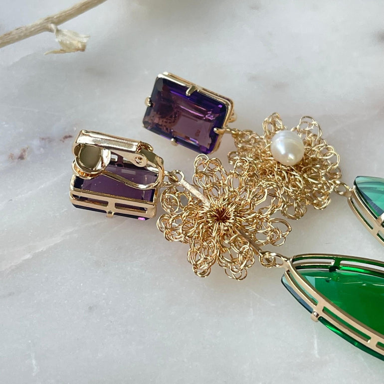 Ohrclip LE CLOS NORMAND: Eleganter und vielseitiger Schmuck mit grünen und lila Kristallen. Clip-Verschluss, Länge: 6,7 cm, Breite: 1,1 cm. 18 K vergoldetes Messing mit funkelnden Kristallen in den Farben Lila und Smaragd. Enthält ein komplettes Ohrring-Paar sowie zusätzliche lila Kristalle für vielseitiges Styling