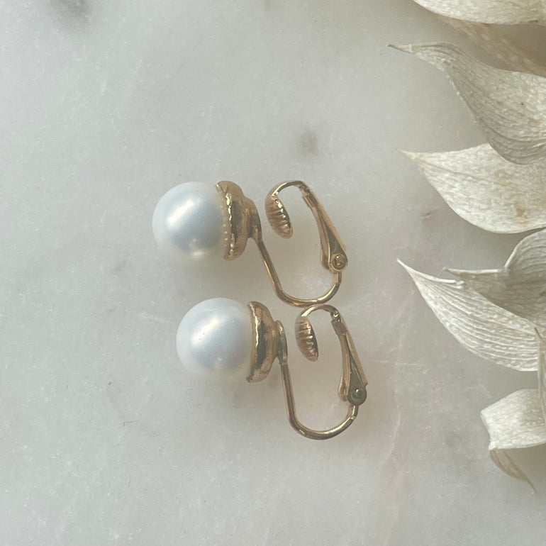Die vergoldeten "ELLA" Perlenohrringe mit Kunstperlen und Clip-Verschluss sind mit ca. 1,0 cm Durchmesser zart und vielseitig. Ein klassisches Design, das jedem Anlass eine subtile Eleganz verleiht – perfekt für zeitlose Schönheit