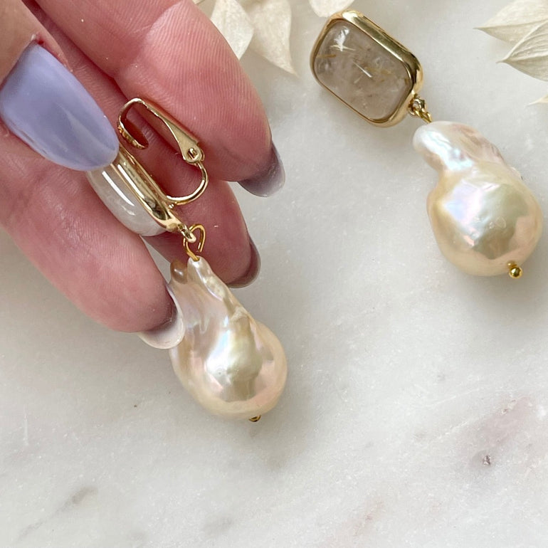 Die "ELLA" Ohrclips mit Rutil-Stein und Barockperlen verkörpern Eleganz und Natürlichkeit. Clip-Verschluss für Komfort. Länge: 4,5 cm, Breite: 1,4 cm (variiert aufgrund natürlicher Perlen). Gewicht: ca. 25,50 g/Paar.  Ein harmonisches Zusammenspiel von Natur und Stil.