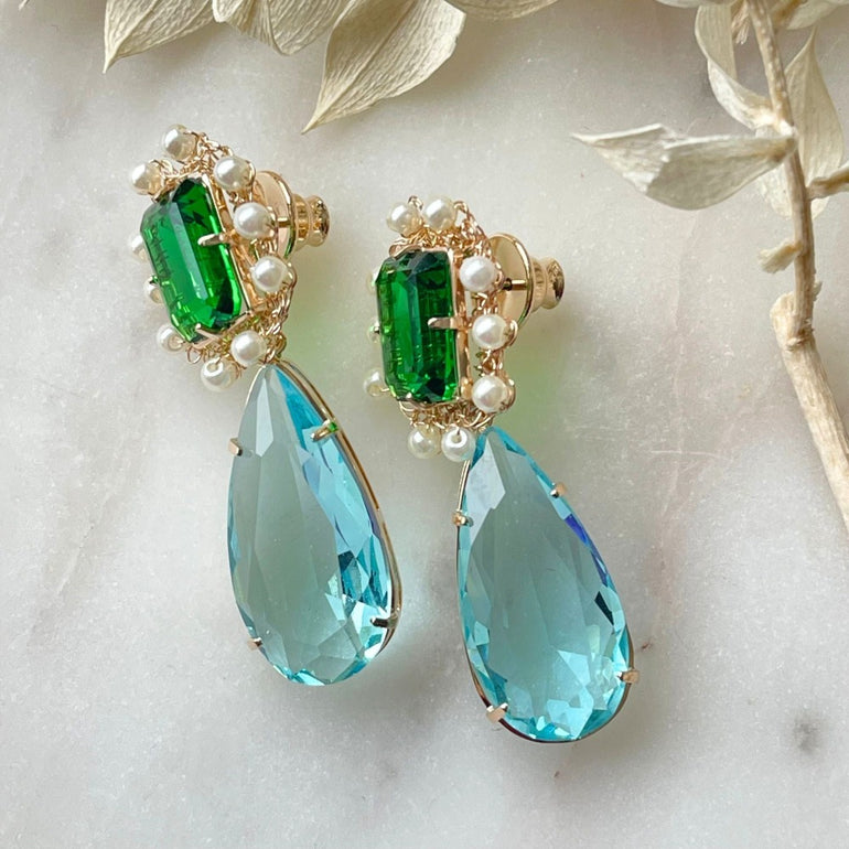 Ohrclips 'LILIBET' mit Smaragd, Aquamarin und Citrin Kristallen. Clip-Verschluss, 5,0 cm Länge, 1,5 cm Breite. 18 K vergoldetes Messing. Flexibel austauschbare Basis. Inklusive Extra-Kristallanhänger. Inspiriert von der Queen’s Jewelry Kollektion.