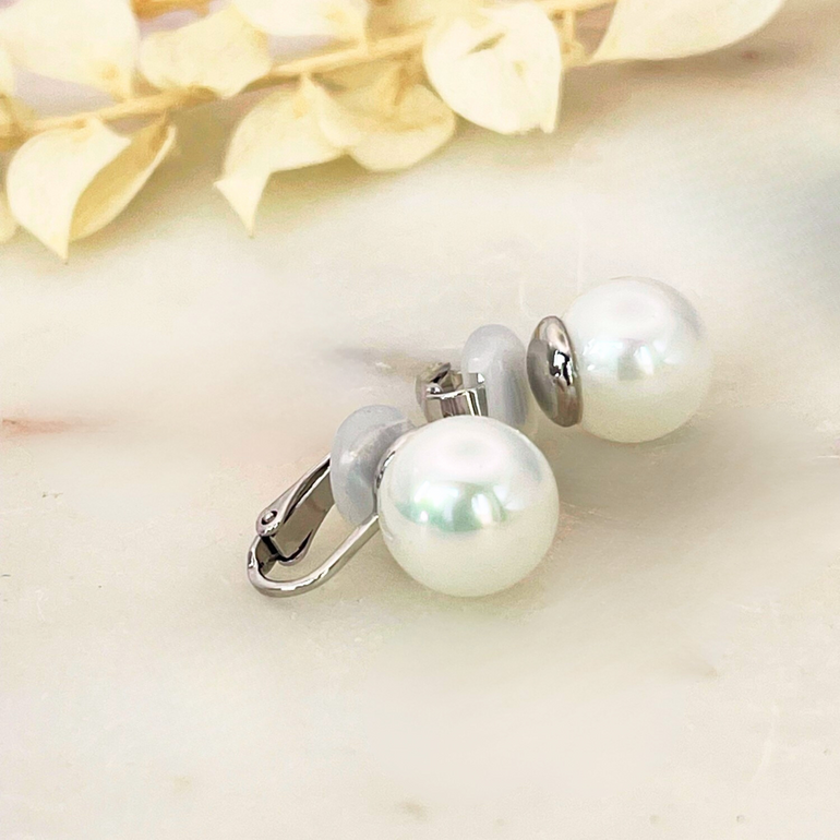 Frontalansicht der rhodinierten Clip Ohrringe CHRISTA CLASSIC mit 10 mm Shell Perlen – Klar, Symmetrisch und Elegant