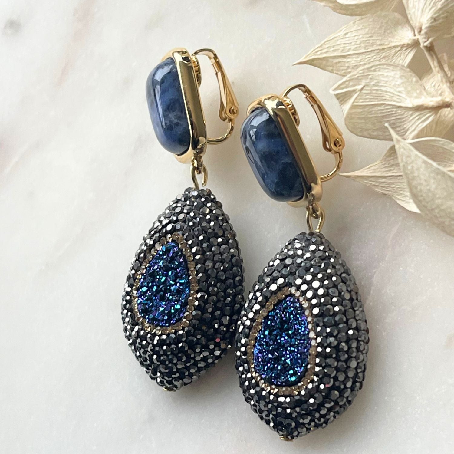 Elegante blaue Ohrringe mit Sodalith-Steinen und funkelnder Markasite. Perfekt für festliche Anlässe, verleihen sie subtile Raffinesse und zeitlose Schönheit. Der tiefblaue Sodalithstein bringt ruhige Eleganz, während die schimmernden Markassite-Details einen Hauch von Glamour hinzufügen