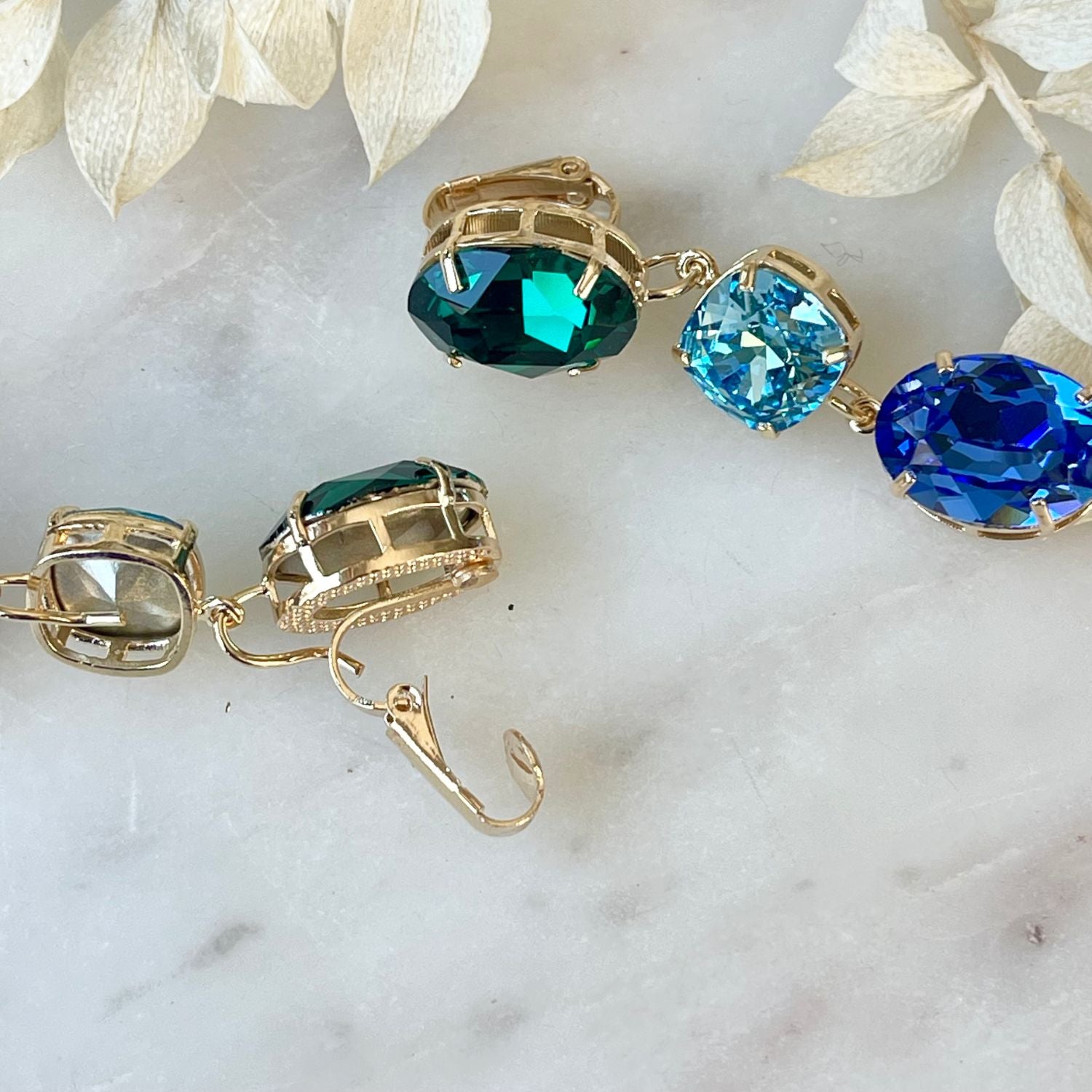 Erleben Sie die Eleganz der "GLOW"-Ohrringe mit  grünen und blauen Kristallen. Die grüne Basis kann separat getragen werden und verleiht einen dezenten, dennoch wunderschönen Touch. Die weltberühmten Swarovski Kristalle sorgen für Glanz und zeitlose Eleganz.