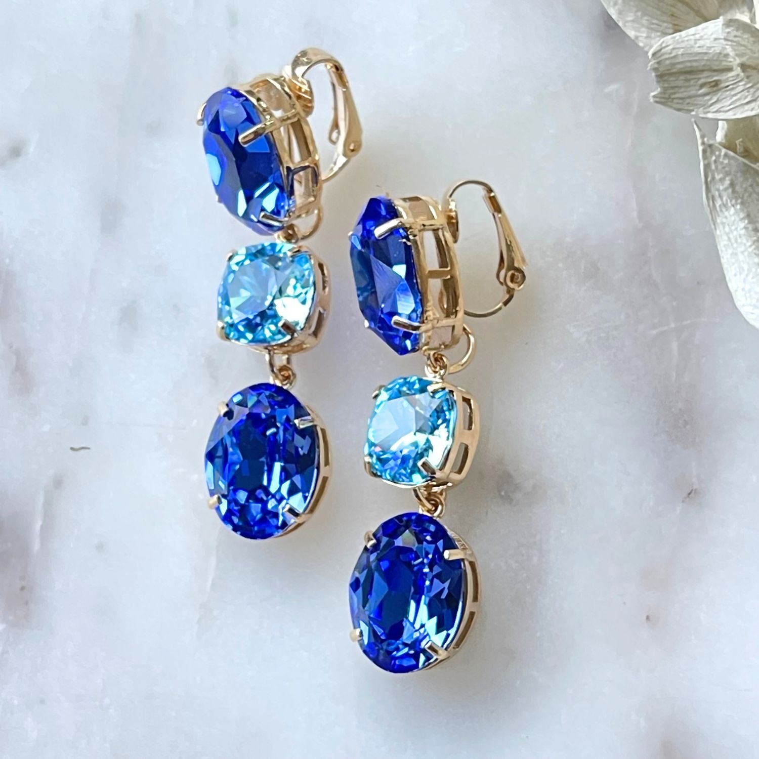 Entdecken Sie die elegante Schönheit der "GLOW" Ohrringe mit schimmernden blauen Kristallen. Die Basis können separat getragen werden, für einen dezenten Look. Diese exquisiten Ohrringe verleihen jedem Outfit einen unvergleichlichen Glanz und zeitlose Eleganz – perfekt für jeden Anlass.