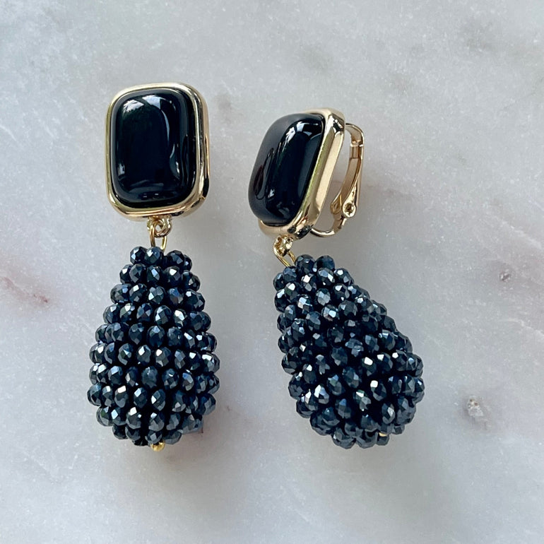 Ohrclips CHARLOTTE mit schwarzem Achat: Zeitlose Eleganz. Clip-Verschluss, 18 K vergoldetes Messing. Länge 4,8 cm, Breite 1,3 cm. Mit Kristall-Anhänger für zeitgenössisches Flair. Einfach anzubringen und bequem zu tragen
